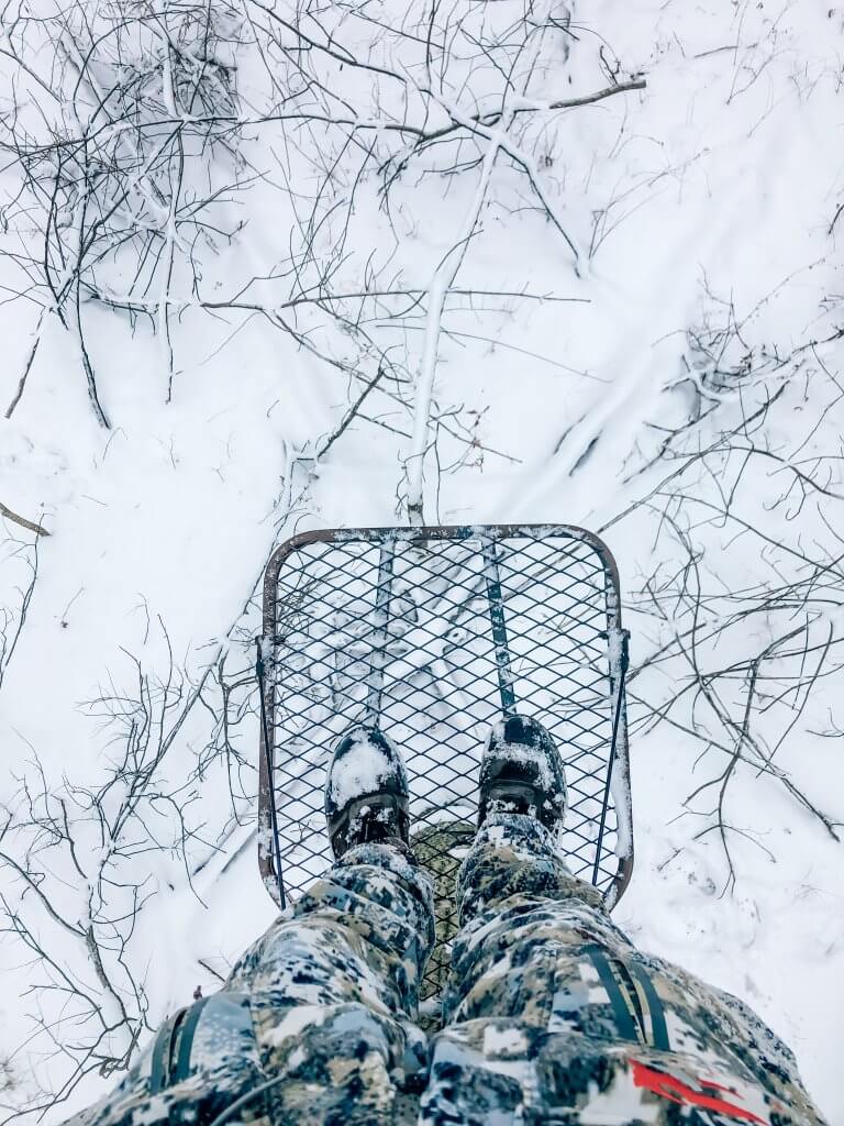 picture of a deer hunter in a tree stand in a snowy background 