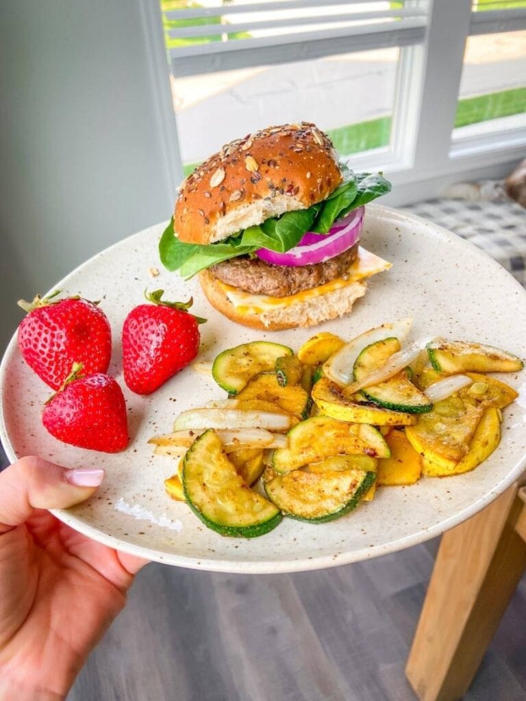 photo of colorful plate of food, hamburger on bun, strawberries and sauteed vegetables