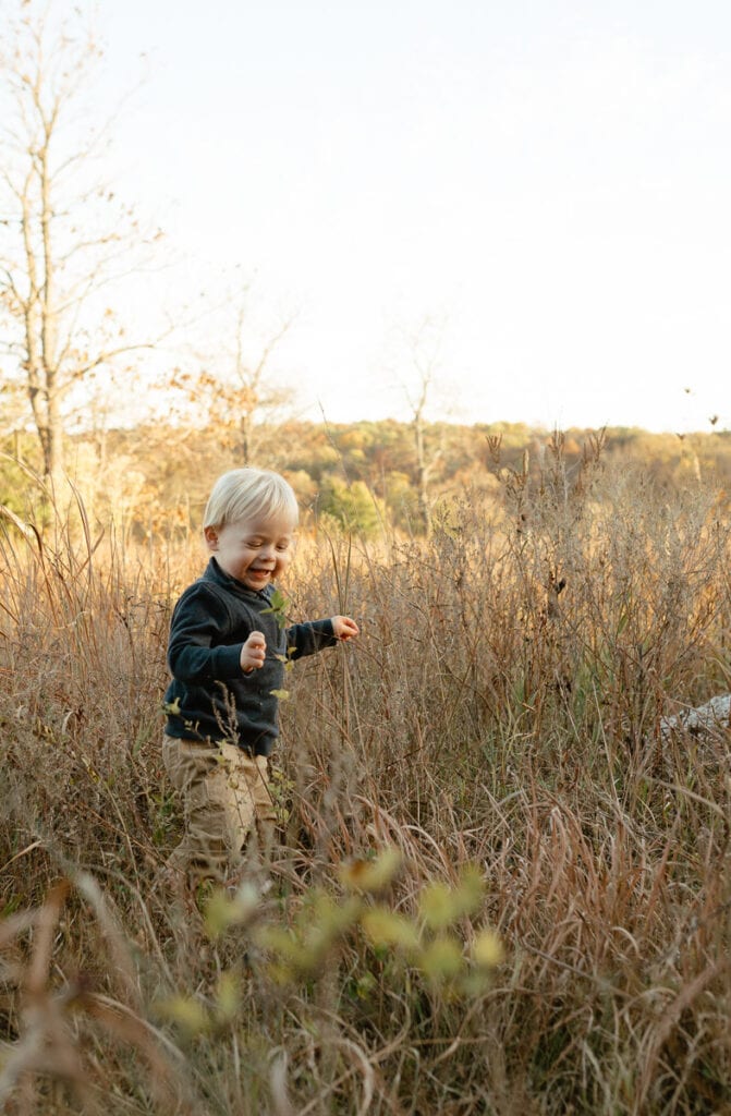 photo of toddler boy running around outside in a field 